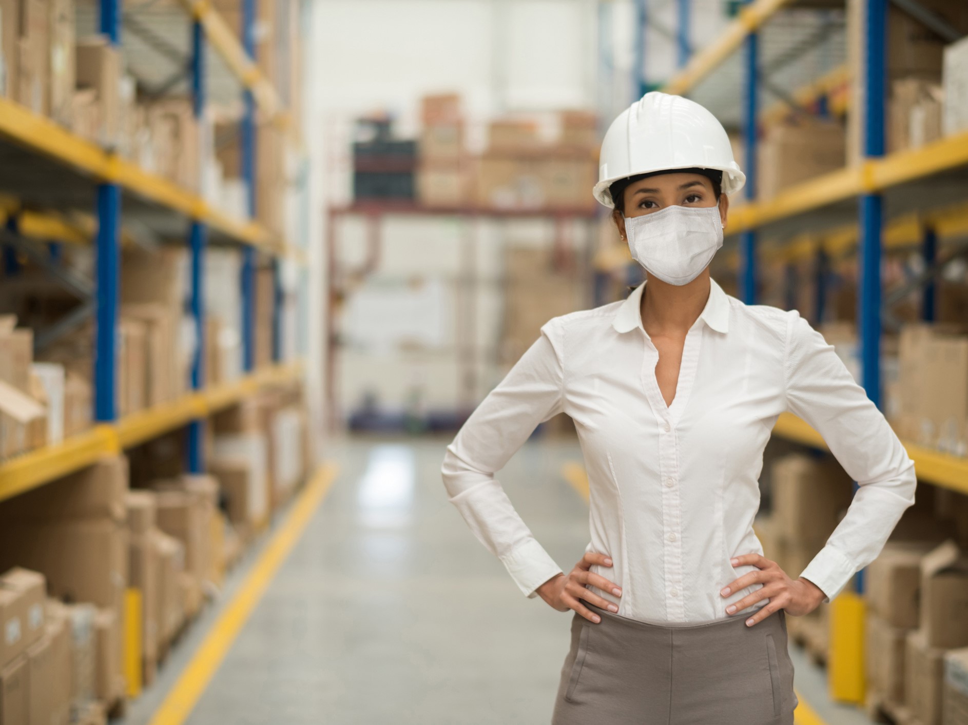 Business woman working at a distribution warehouse wearing a facemask to avoid COVID-19