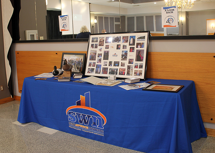 Buffet table covered with SWN tablecloth topped with photos, books, and other memorabilia for the past 40 years.